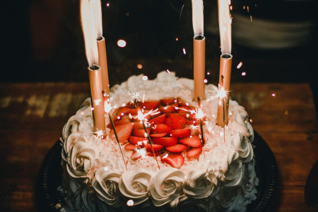 Celebrate with a festive strawberry-topped birthday cake adorned with sparkler candles, creating a joyful atmosphere.