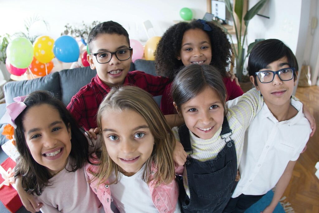 Smiling children enjoying a joyful birthday celebration indoors with colorful balloons.